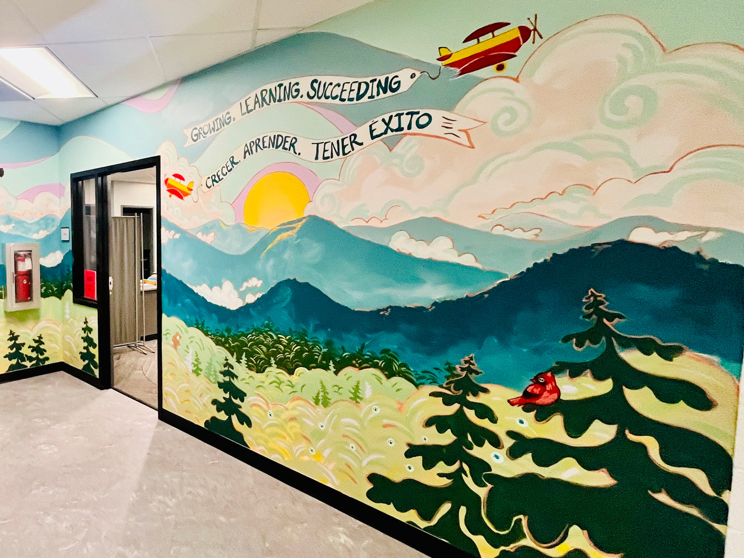 Colorful mural with a landscape, sun, and airplane on a wall.